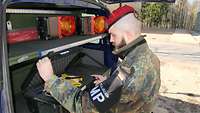 Ein Soldat steht am Heck eines Kraftfahrzeugs und blickt in eine Kiste