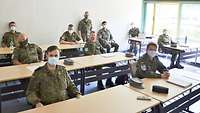 Zehn Soldaten sitzen mit viel Abstand zueinander in einem Unterrichtsraum