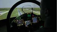 Ein Soldat sitzt in einem Cockpit vor einer simulierten Landebahn