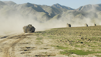 Vier Panzer fahren mit Abstand hintereinander. Dahinter erstreckt sich eine steinige Gebirgskette.