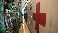Im Frachtraum: Container von der Seite mit rotem Kreuz
