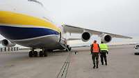 Die Antonov steht auf dem Rollfeld. Zwei Personen mit Warnweste gehen auf sie zu. 