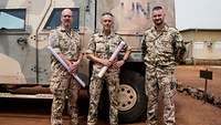 Ein Gruppenbild dreier Soldaten vor einem Fahrzeug