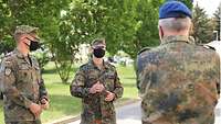 Generalstabsarzt Dr. Baumgärtner unterhält sich mit zwei Soldaten, die Mund-Nasen-Abdeckung tragen
