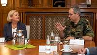 Mehrere Soldaten und eine Frau sitzen an einem großen Besprechungstisch.
