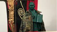 Hinter einem Altar mit einer aufgeschlagenen Bibel steht eine Luther-Statue mit einer umgehängten Militärjacke.