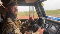 Innenraum des Fahrzeuges, ein Soldat hinter dem Steuer lächelt und zeigt den ausgestreckten Daumen