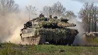 Ein Kampfpanzer Leopard 2A6 fährt im Gelände und wirbelt Staub auf