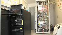 Ein Raum mit vielen IT-Geräten, einem Schaltschrank und einem Server