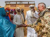 CIMIC-Projekt in Mali: Deutscher Soldat im Gespräch mit malischen Bewohnern Soldat gibt einer malischen Frau die Hand, drumherum weitere Personen