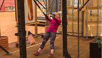Eine Soldatin in ziviler Sportbekleidung treibt Sport mit Hilfe eines TRX Bandes