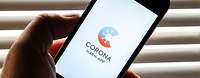 Eine Hand hält ein Smartphone, auf dem das Logo der Corona-Warn-App der Bundesregierung angezeigt wird