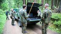 Aus einem Transportfahrzeug der Bundeswehr entladen Soldaten Werkzeug zur Borkenkäferbekämpfung.