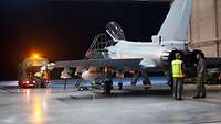 Ein Eurofighter steht bei Nacht in einer Halle auf dem Flugplatz Ämari. Ein Tankwagen betankt den Jet nach dem Flug.