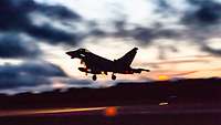 Ein Jagdflugzeug vom Typ Eurofighter startet in Ämari in Estland zum einem Nachtflug. Im Hintergrund die untergehende Sonne.