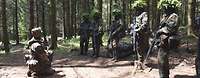 Gefechtsdienstausbildung im Wald Mehrere Soldatinnen und Soldaten im Gefechtsanzug mit Tarnung stehen im Wald