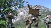 Vier Soldaten stehen auf einer Wiese mit Tafeln in den Händen, hinter ihnen erhebt sich ein Berg.