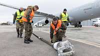 Der Tankstutzen. Mehrere Soldaten in Warnwesten betrachten den Tankstutzen des Airbus A330.