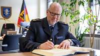 Ein Mann in Uniform trägt sich in ein Gästebuch ein