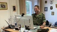 Oberstleutnant Andreas Verfürth sitzt vor seinem Schreibtisch und blickt freudig gespannt auf seinen Bildschirm.
