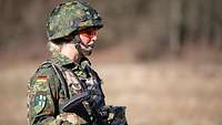 Stabsapotheker Schnölzer steht im Feldanzug und Waffe im Gelände