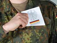 Die Soldaten und Soldatinnen der Bundeswehr sind dem Grundgesetz verpflichtet. Soldat zieht Grundgesetzbuch aus der linken Brusttasche seiner Uniform.