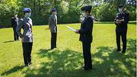 Mehrere Soldatinnen und Soldaten stehen mit Mund-Nase-Schutz auf einer Wiese