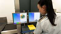 Gepäckscanner im Test Eine Soldatin schaut auf den Monitor des Gepäckscanners, auf dem der Inhalt eines durchleuchteten Koffers zu sehen ist.