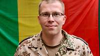 Ein Soldat vor der malischen Flagge