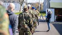 Mehrere Soldaten und Zivilisten stehen in einer Reihe