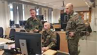Drei Soldaten stehen im Lagzentrum vor einem Bildschirm und informieren sich.