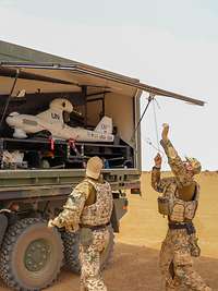 Zwei Soldaten stehen neben dem LKW. Ein Soldat schließt die Klappe der Ladefläche