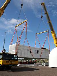 Zwei Kräne heben einen Container auf eine Betonplatte