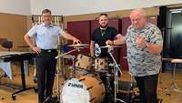 Gruppenbild - Drei Musiker stehen an einem Schlagzeug