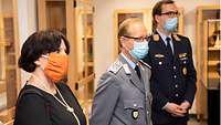 Drei Personen mit Mundschutz in einem Ausstellungsraum