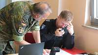 Ein Soldat spricht mit einem Polizisten über mögliche Amtshilfe.
