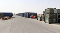 Entlang eines Weges stehen rechts und links Container aufgereiht. Dazwischen steht ein Gabelstapler
