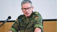 Generalstabsarzt Dr. Stephan Schoeps sitzt vor zwei Mikrofonen