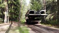 Ein Panzer mit einer Schnellbrücke fährt entlang eines Waldweges