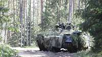Ein Schützenpanzer steht an einer Weggabelung, der Kommandant des Fahrzeugs schaut aus seiner Luke