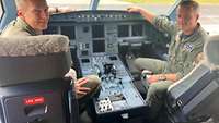 Zwei Soldaten sitzen in im Cockpit des A330 MRTT und schauen über ihre Schultern.