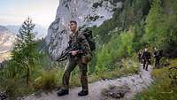 Vier Soldaten marschieren auf einem grauen, schmalen Pfad einen Berg hoch. 