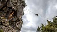 Ein Soldat überwindet mit einem Seilsteg eine tiefe Schlucht zwischen dem grauen Felsgestein. 