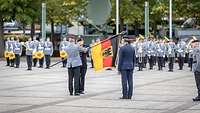 Ein Soldat nimmt eine Truppefahne entgegen.