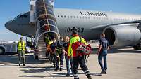 Mehrere Personen gelangen über eine Boardingtreppe in das Flugzeug