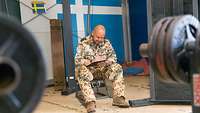 Ein Soldat sitzt auf einem Sportgerät