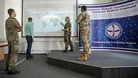 Four people are standing in front of a global map