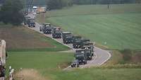 Militärkraftfahrzeuge fahren über eine Landstraße