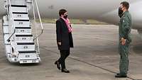 Vor einem deutschen Regierungsflugzeug begrüßt ein Soldat eine Frau in Zivilkleidung mit militärischem Gruß.