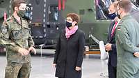 Ein Soldat der Bundeswehr und eine Frau in Zivil stehen vor einem großen Militärhubschrauber.